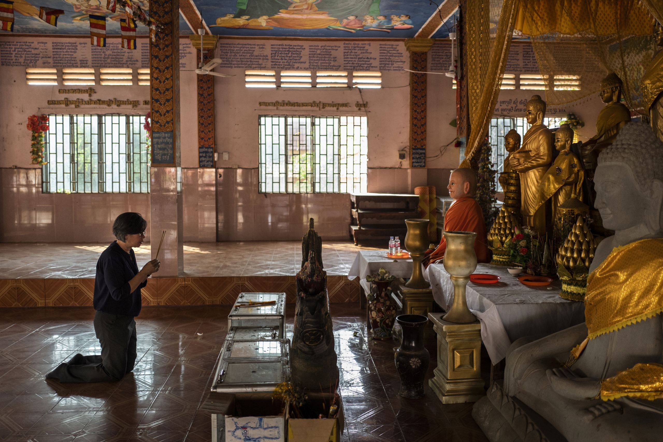 Vichuta Ly, 54, prays at Buddhist temple along the national road. Her family found shelter there while fleeing the capital at the start of the Khmer Rouge regime.