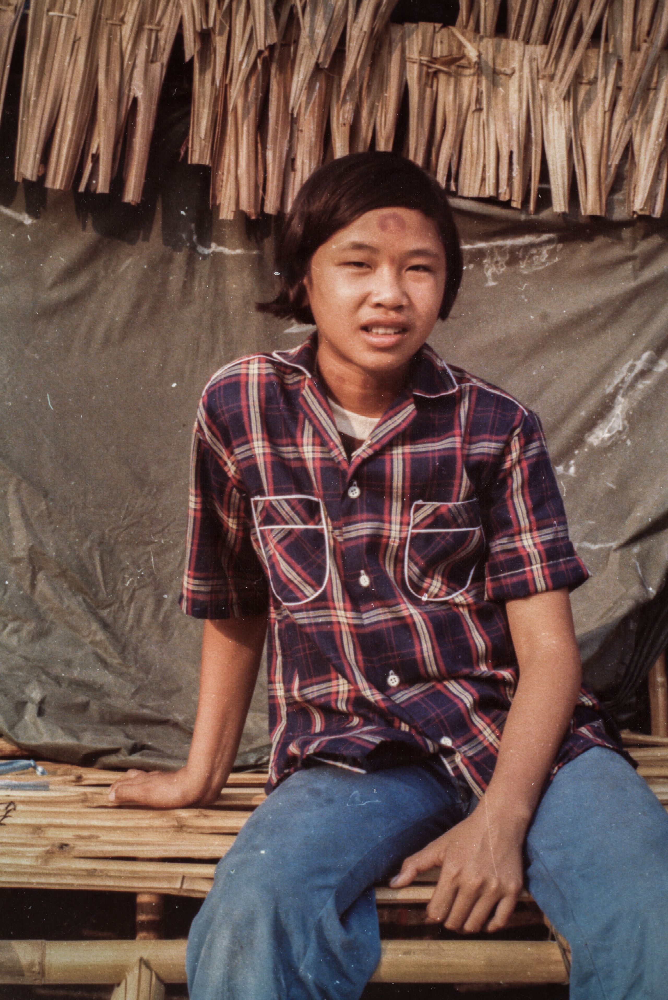 14 year old Vichuta Ly sitting on a bench inside Sa Keao refugee camp in Thailand. This is where she met Anne Watts, a Save the Children nurse.